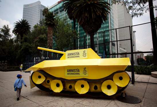 A child walks around a fake tank parked outside the U.S. embassy during a protest held by Amnesty International in Mexico City