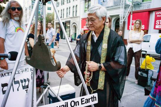 Rev. Earl Ikeda of the NYC Buddhist Church rings the peace bell in Union Square Park Photo (c) Joan Roth